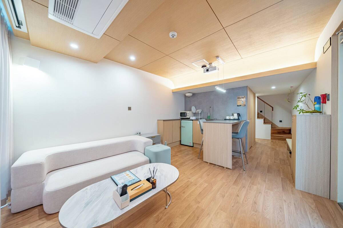 Una sala de estar moderna con un sofá, una mesa de centro y una cocina al fondo.