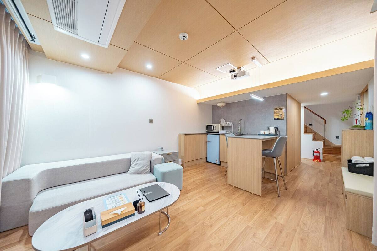 Un apartamento moderno con sala de estar, kitchenette y una escalera que lleva a un piso superior.