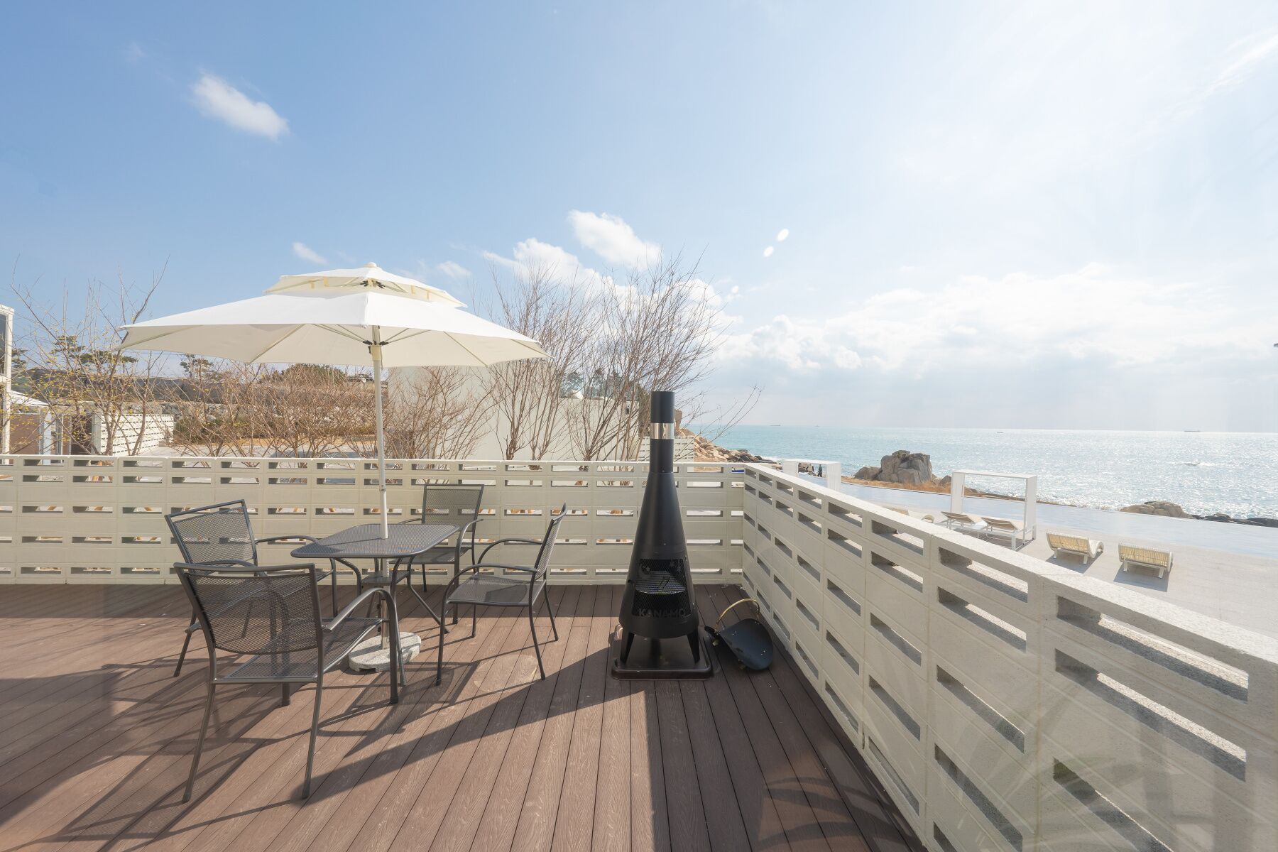 An outdoor patio with a grill, chairs, and an umbrella.