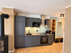 A modern kitchen with grey cabinetry, a built-in oven, and a microwave.