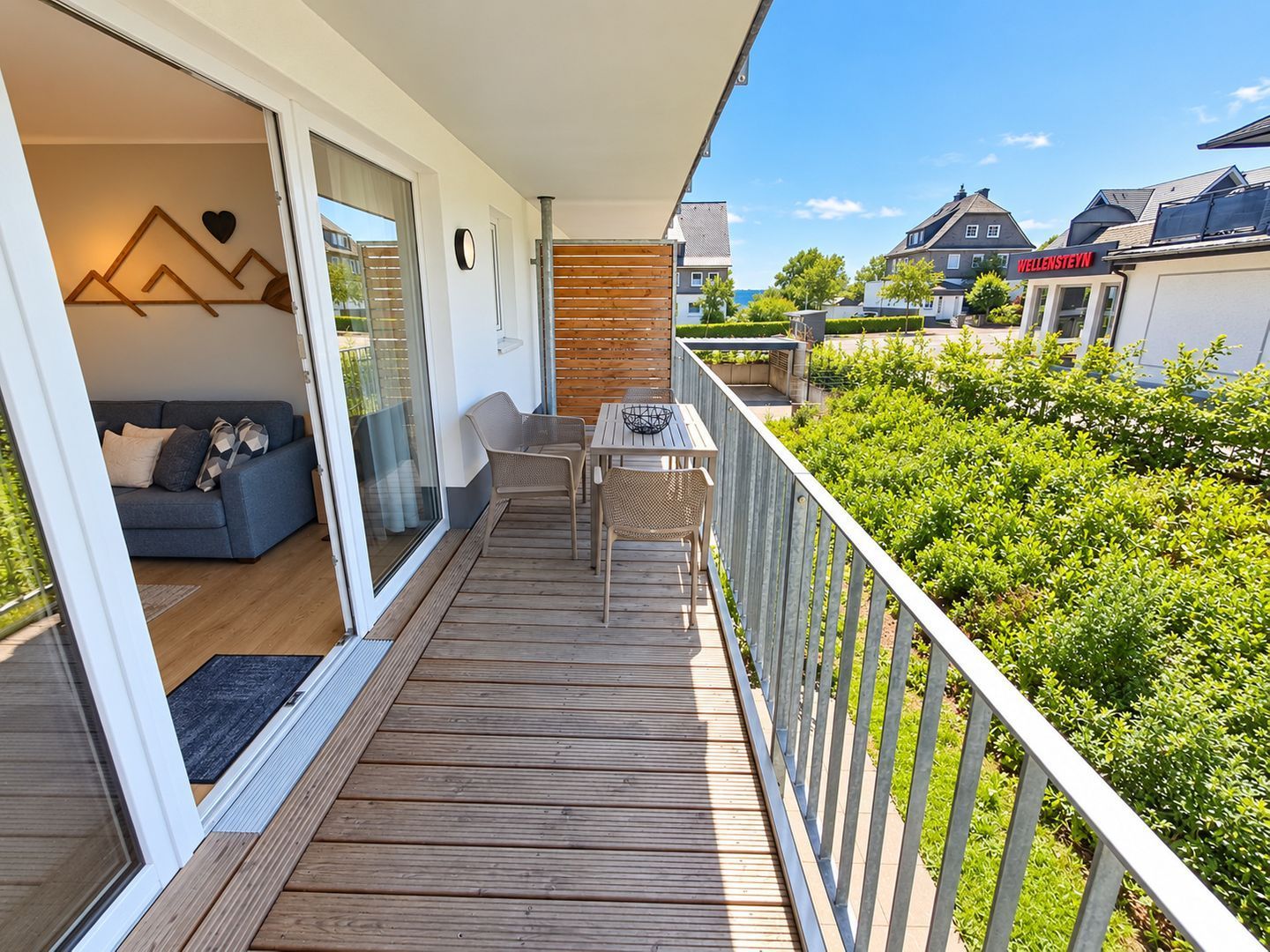 A balcony with a wooden deck, a sofa, and a table with chairs.