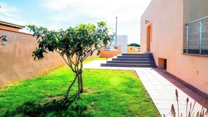 A modern building with a flat roof, a small tree in the foreground, and a staircase leading to a door. - Golf-view villa with pool (Chiclana de la Frontera)