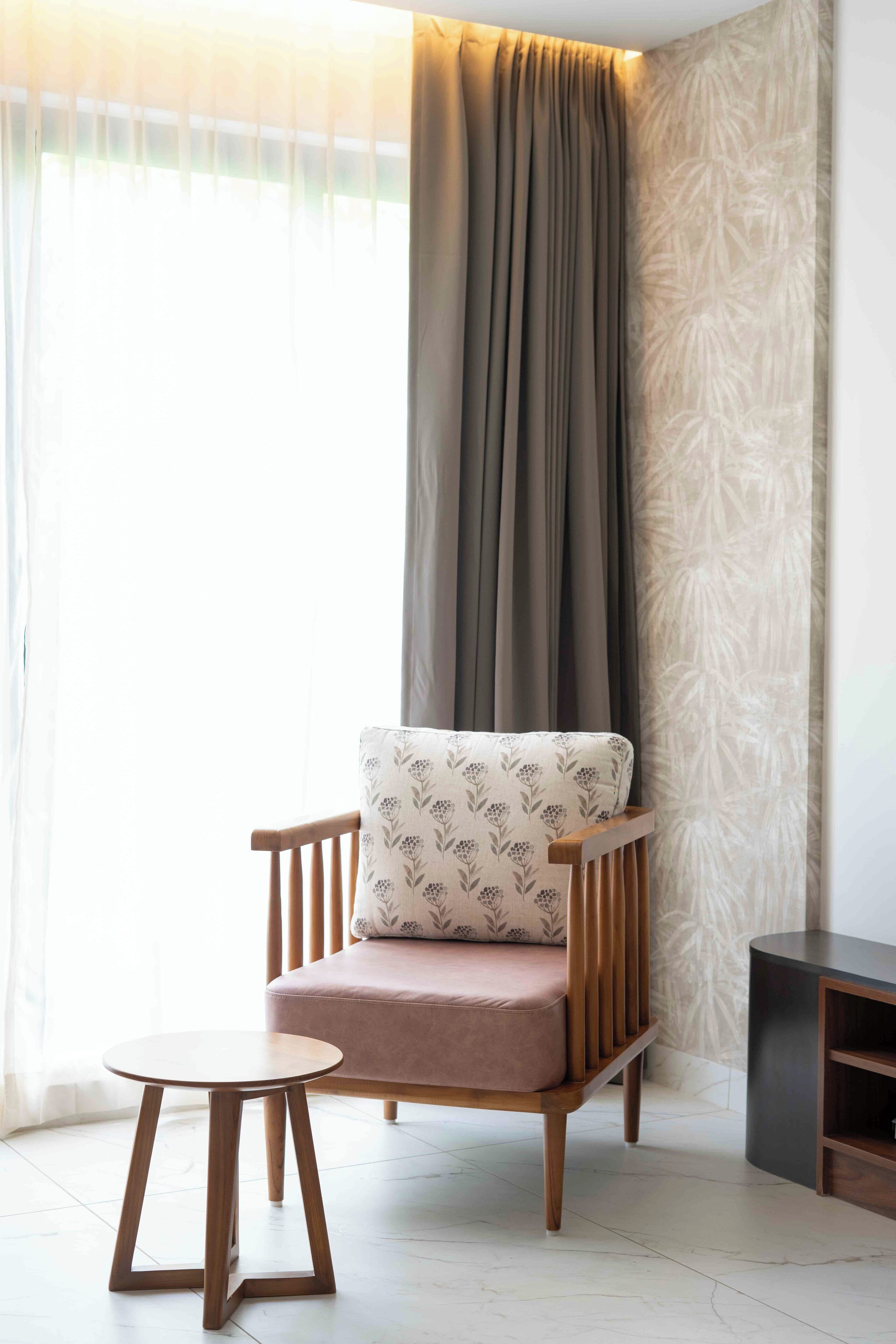 A modern room with a wooden chair, a small round table, and a dark wooden cabinet.