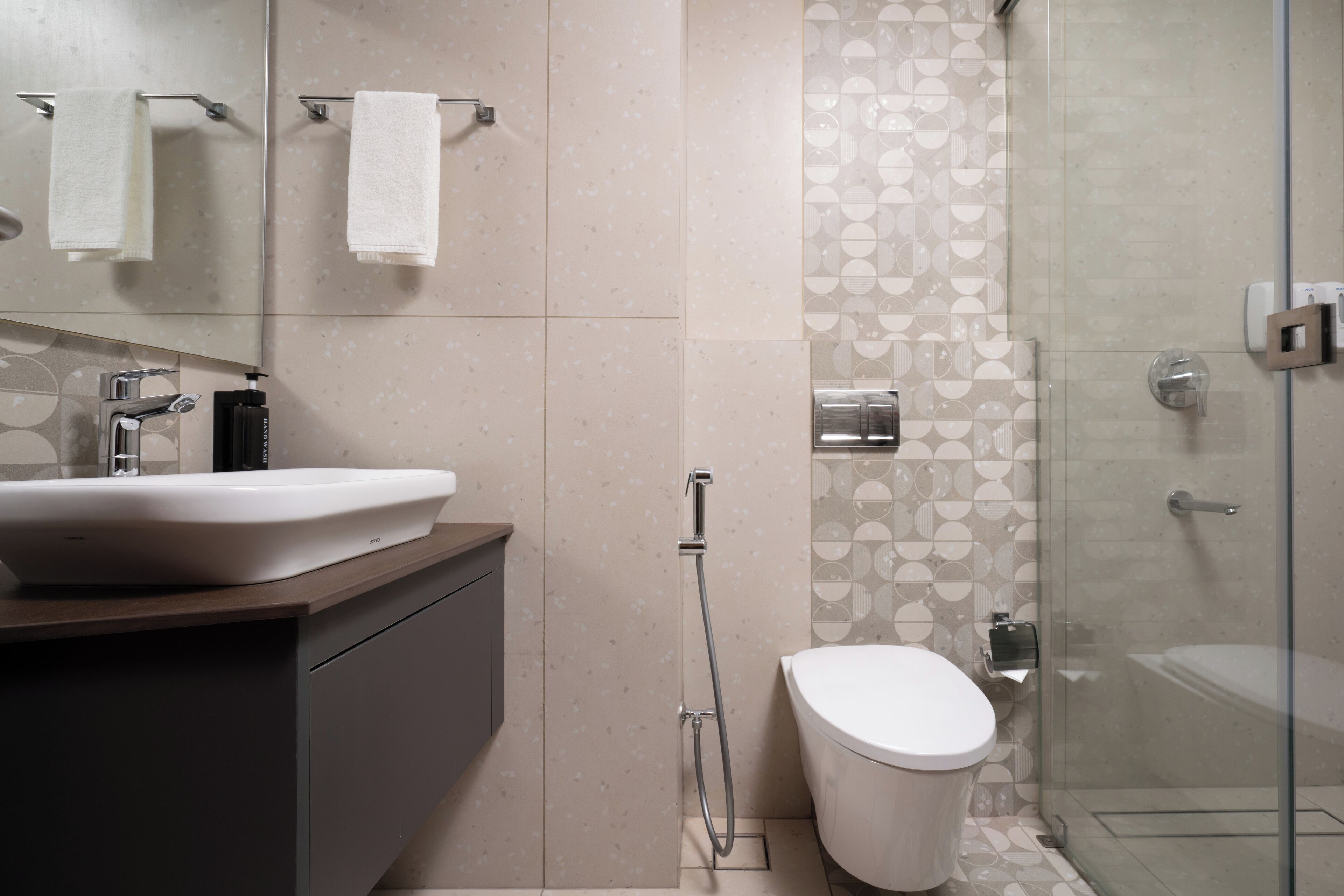 A modern bathroom with a large sink, toilet, and glass shower enclosure.