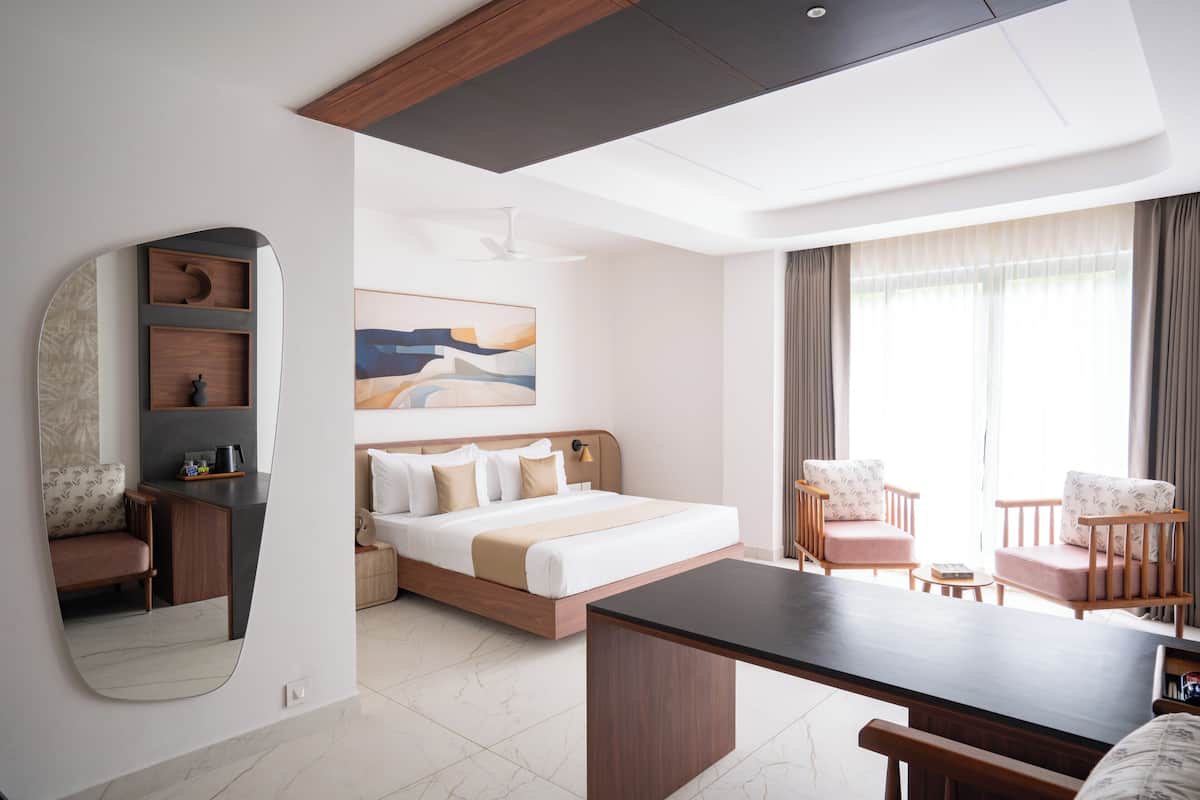 A modern hotel room with a bed, seating area, and a desk.