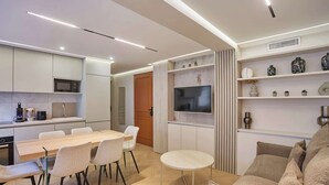 A modern kitchen with a dining area, a TV, and a seating area with a sofa and a small round table. - Sublime AC Apartment Eiffel Tower Champs de Mars (Paris)