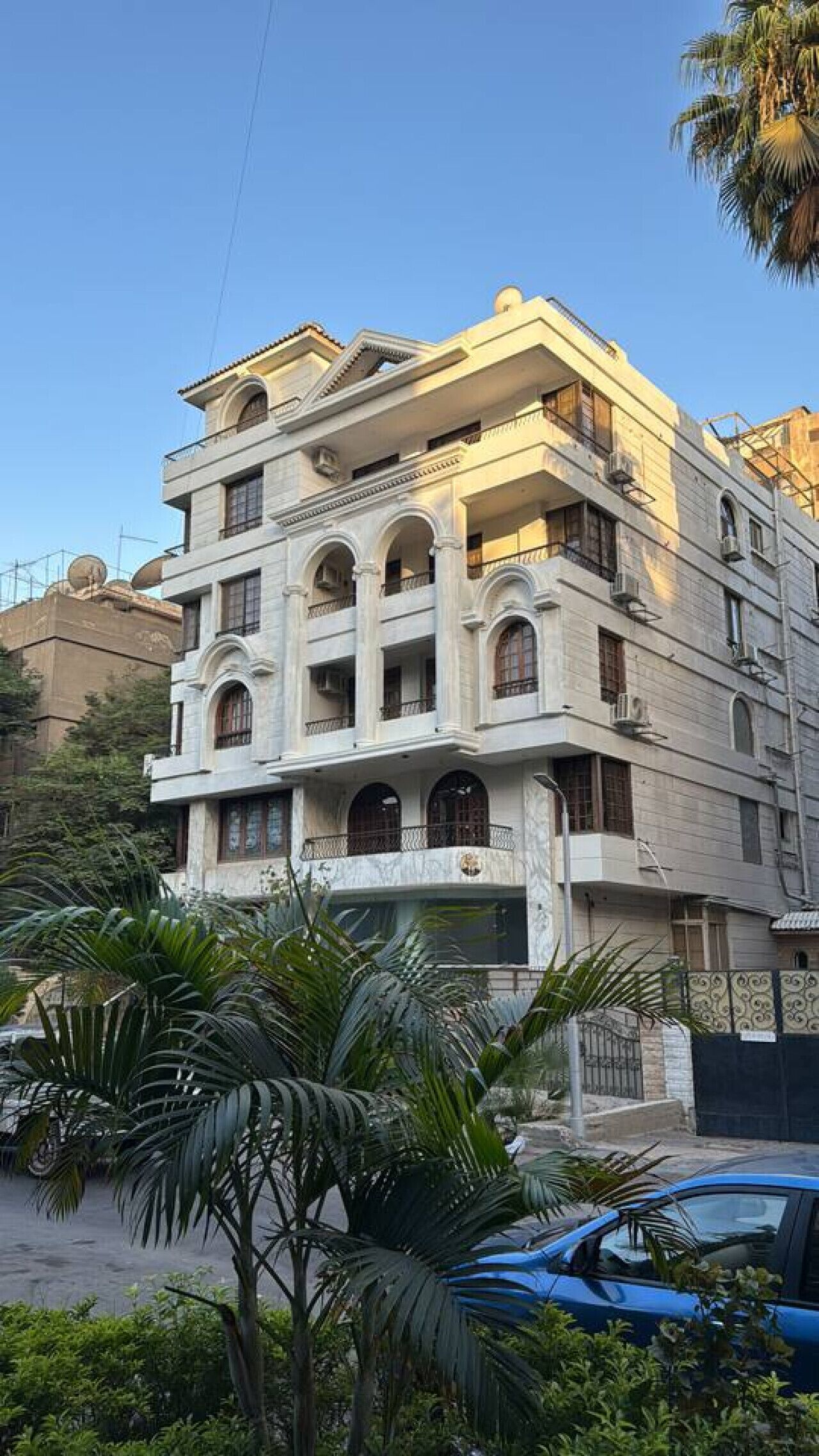 A multi-story building with balconies, arched windows, and a gated entrance.