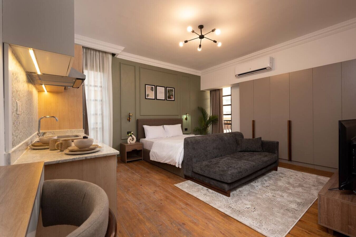 Une chambre d’hôtel moderne équipée d’un lit, d’un canapé, d’un bureau avec une chaise et d’une télévision.