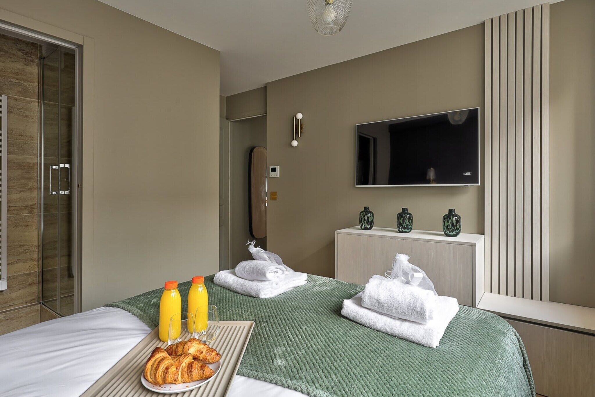 Hotellihuone, jossa on sänky, aamiaistarjoilu, televisio ja minibaari.