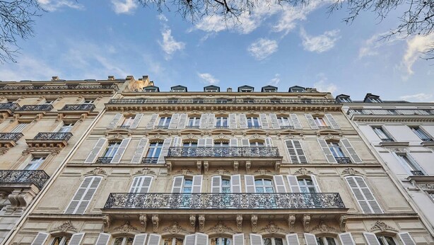 A multi-story building with ornate balconies and shutters.