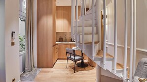 A modern kitchen with wooden cabinets, a sink, and a dining area with a chair and table.