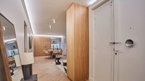 Ein modernes Interieur mit Holzboden, einem Essbereich mit Tisch und Stühlen sowie einer weißen Tür mit rundem Spiegel.