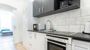 A modern kitchen with white cabinets, a black countertop, a built-in oven, and a dishwasher. - Cozy 1BR Apartment in Prime Location (Vienna)