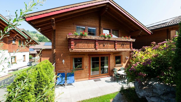 Una cabaña de madera con balcón, zona de patio y vistas del paisaje circundante.