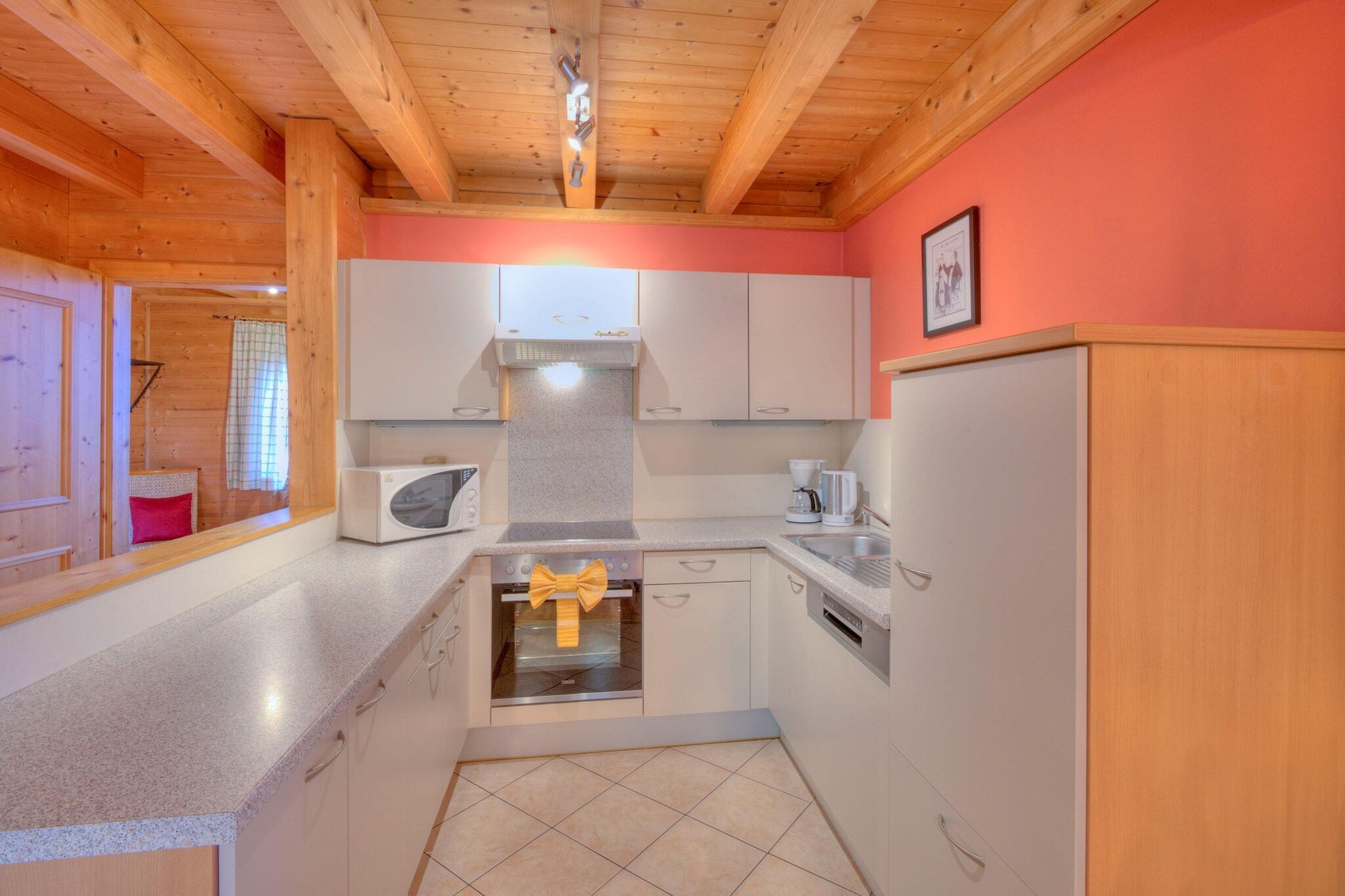 A compact kitchen with white cabinets, a microwave, a stove, and a sink.