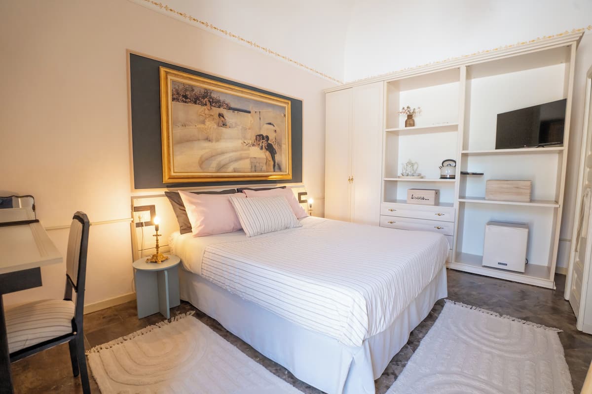 A bedroom with a large bed, bedside tables, a TV, and a wardrobe.