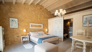 Un dormitorio con cama, mesitas de noche, una silla, una mesa y un armario.