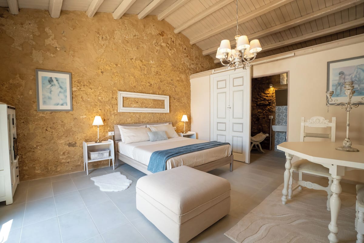 A bedroom with a bed, bedside tables, a chair, a table, and a wardrobe.