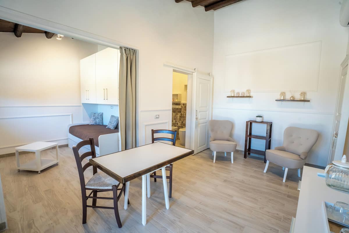 A cozy living room with a dining table, two chairs, a sofa, and a kitchen area visible through an open door.