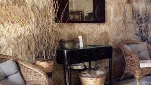 Una habitación rústica con muebles de mimbre, una pared de piedra y un espejo.