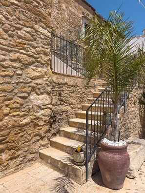 A stone staircase with metal railings leading to a building entrance. - Feudo Nobile (Gela)