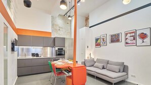 Eine moderne Küche mit grauen Schränken, einem Esstisch mit Stühlen und einem grauen Sofa im Wohnbereich.