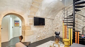 Ein modernes Interieur mit einer Steinwand, einer schwarzen Wendeltreppe und einem an der Wand befestigten Flachbildfernseher.