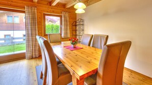 A wooden dining table with four chairs, a potted plant, and a hanging light fixture.