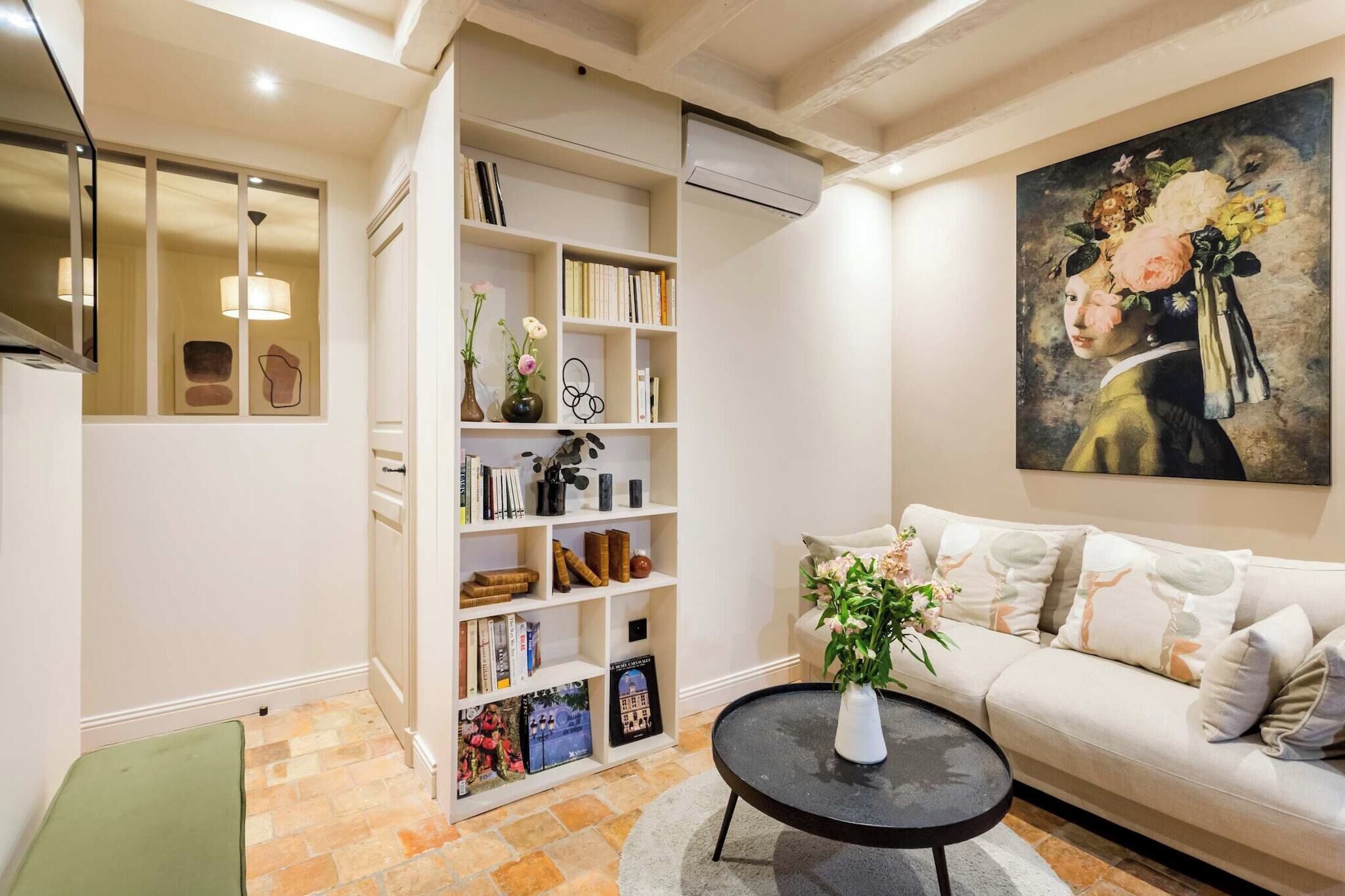 A living room with a sofa, a coffee table, a bookshelf, and a painting on the wall.