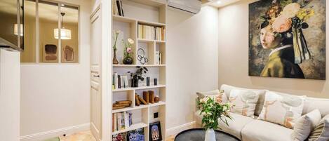 A living room with a sofa, a coffee table, a bookshelf, and a painting on the wall.