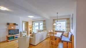 Ein modernes Wohnzimmer mit einer Couch, einem Esstisch und einem Fernseher.
