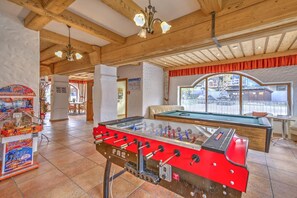 A room with a foosball table, a pool table, and a billiards table.