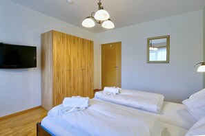 A hotel room with two beds, a wardrobe, a television, and a mirror. - Wildschönau Alpine Vicky Apartment (Wildschönau)