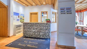 Un'area reception con un bancone in pietra, soffitto in legno e un tappetino con scritte.