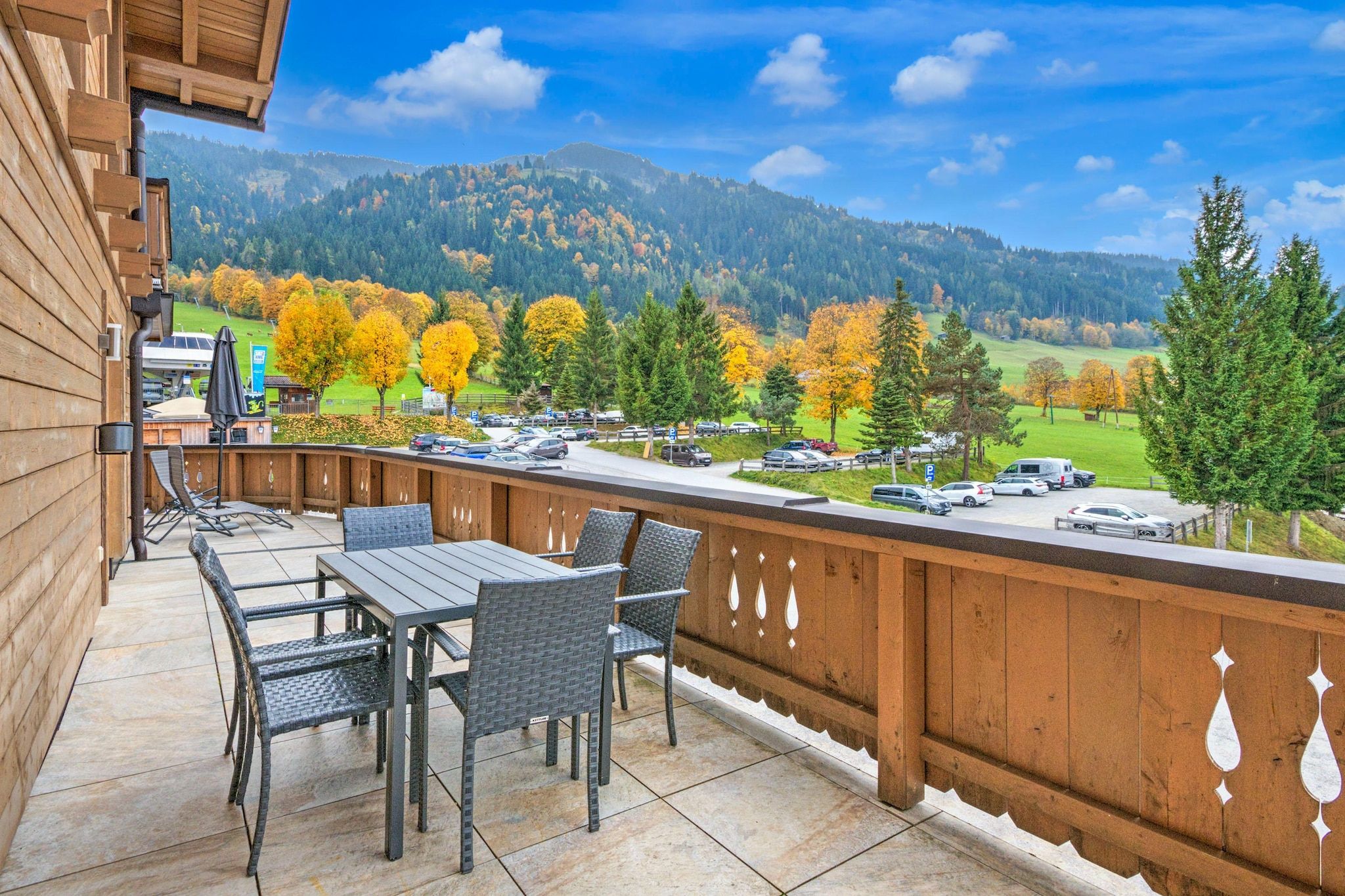 Un balcon avec coin salon extérieur et vue sur un parking et les montagnes.
