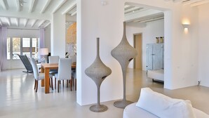 Ein modernes Wohnzimmer mit Essbereich, ausgestattet mit einem weißen Sofa, einem Esstisch mit Stühlen und zwei hohen Stehlampen.