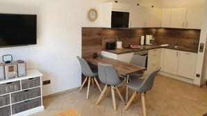 Een moderne keuken met een houten aanrecht, witte kastjes en een eethoek met een houten tafel en vier stoelen.
