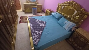 Een slaapkamer met een bed, een dressoir, een spiegel en een deur.