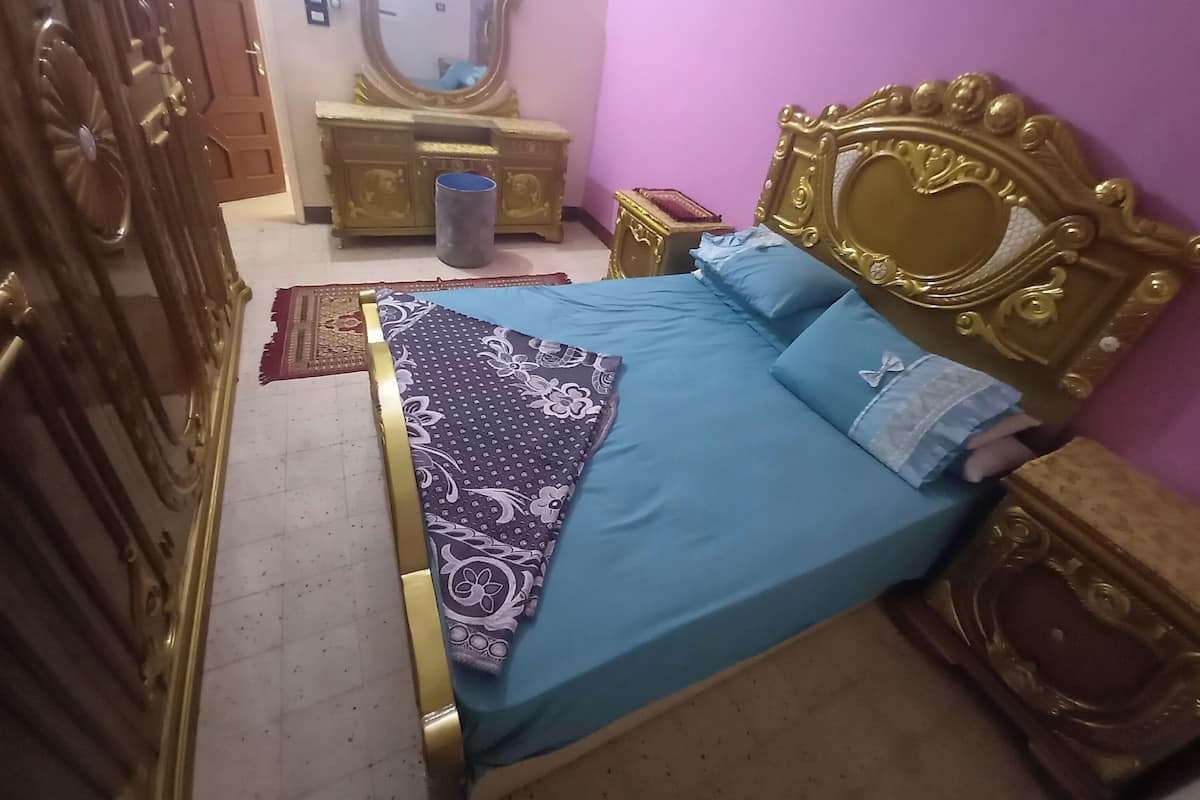 A bedroom with a bed, a dresser, a mirror, and a door.