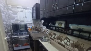 Een keuken met donkere kastjes, een fornuis en een betegelde spatwand.