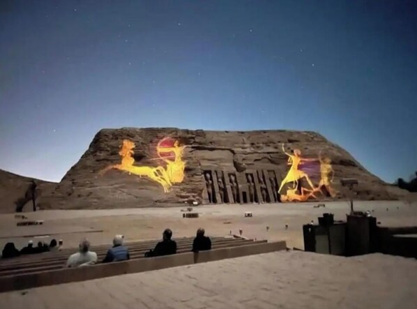 A large rock formation with hieroglyphs and a night sky.
