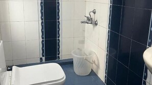 Une salle de bain avec des toilettes blanches, un espace douche et un sol carrelé de carreaux bleus.
