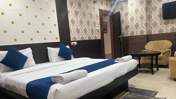 Une chambre d’hôtel avec un grand lit, une petite table, une chaise et un téléviseur fixé au mur.