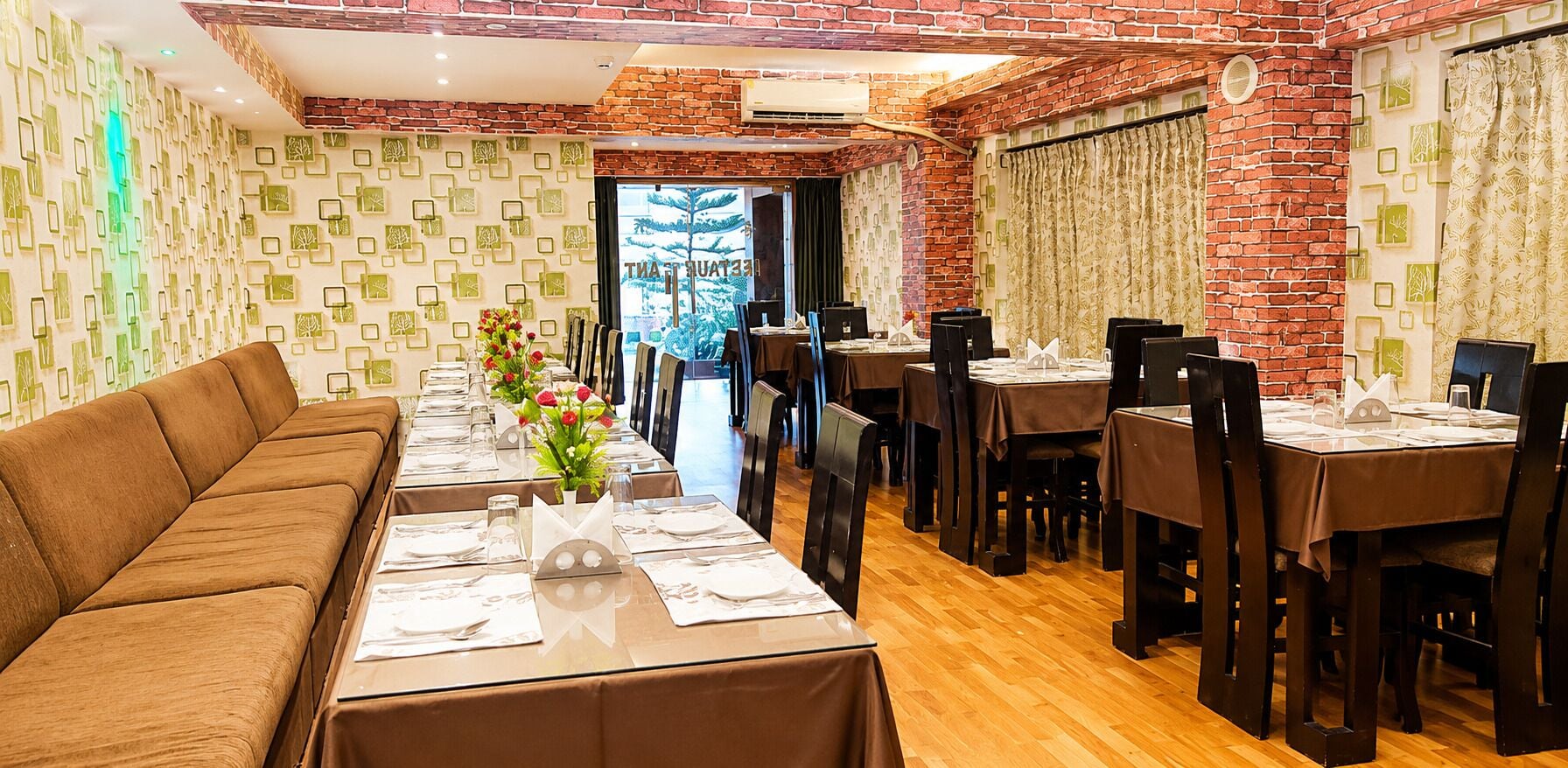 A restaurant with a brick wall, a long dining table, and a sofa.