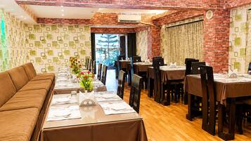 A restaurant with a brick wall, a long dining table, and a sofa.