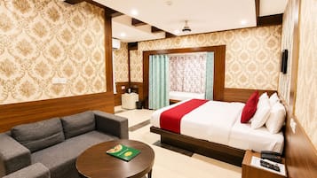 Habitación de hotel con cama, sofá, una mesita y una mesita de noche con teléfono.