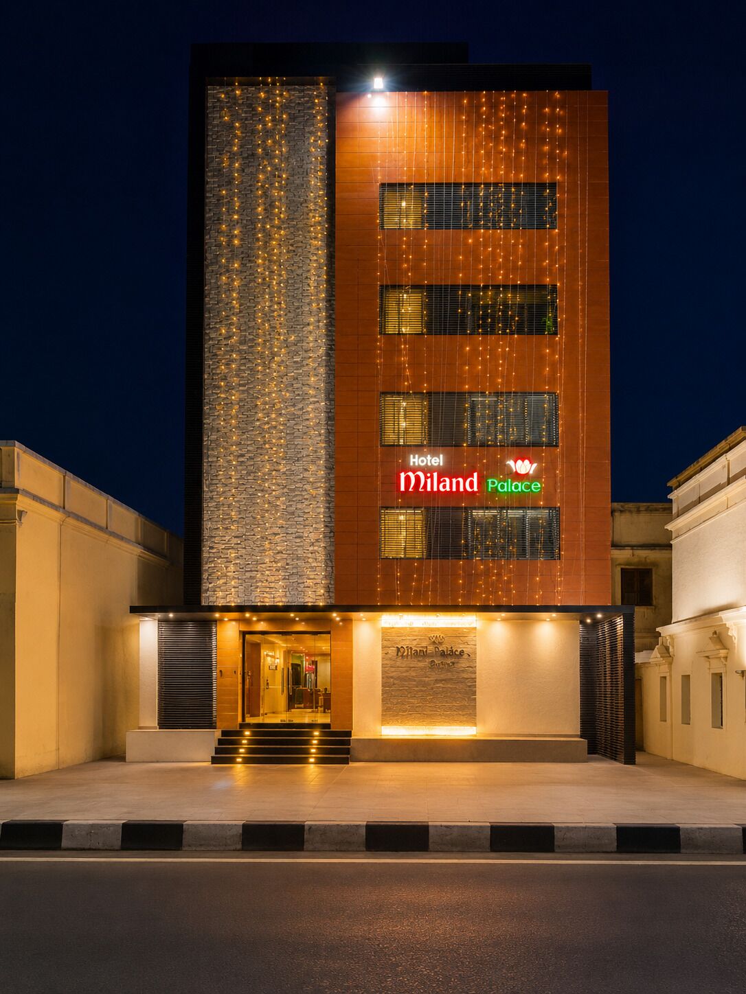 A modern hotel building with a stone facade, illuminated signage, and a welcoming entrance.