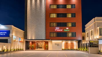 Hotellin julkisivu on moderni, sen yllä on suuri ja selkeästi näkyvä kyltti, jossa lukee »Hotel Miland Palace», ja sisäänkäyntialue on hyvin valaistu.
