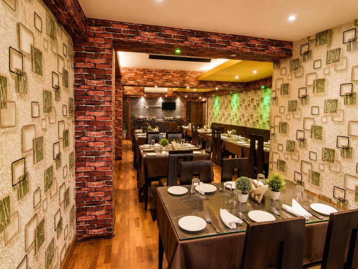 Un restaurant aux murs de briques, aux planchers de bois et aux tables dressées pour le service.