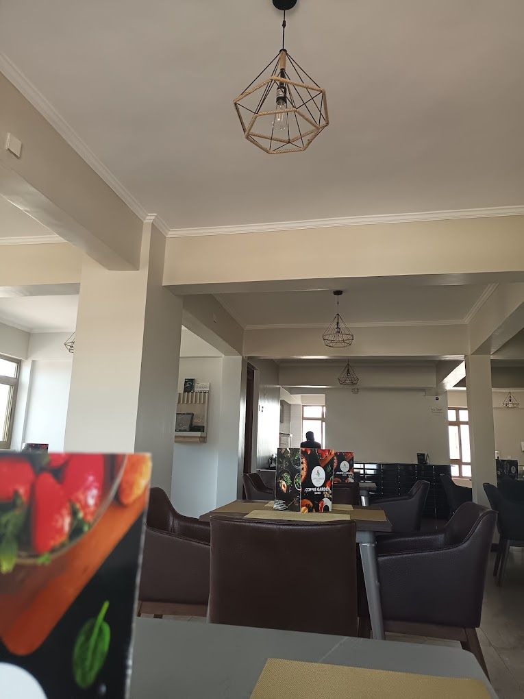 A spacious room with a dining area featuring a table and chairs, a hanging light fixture, and a coffee station.